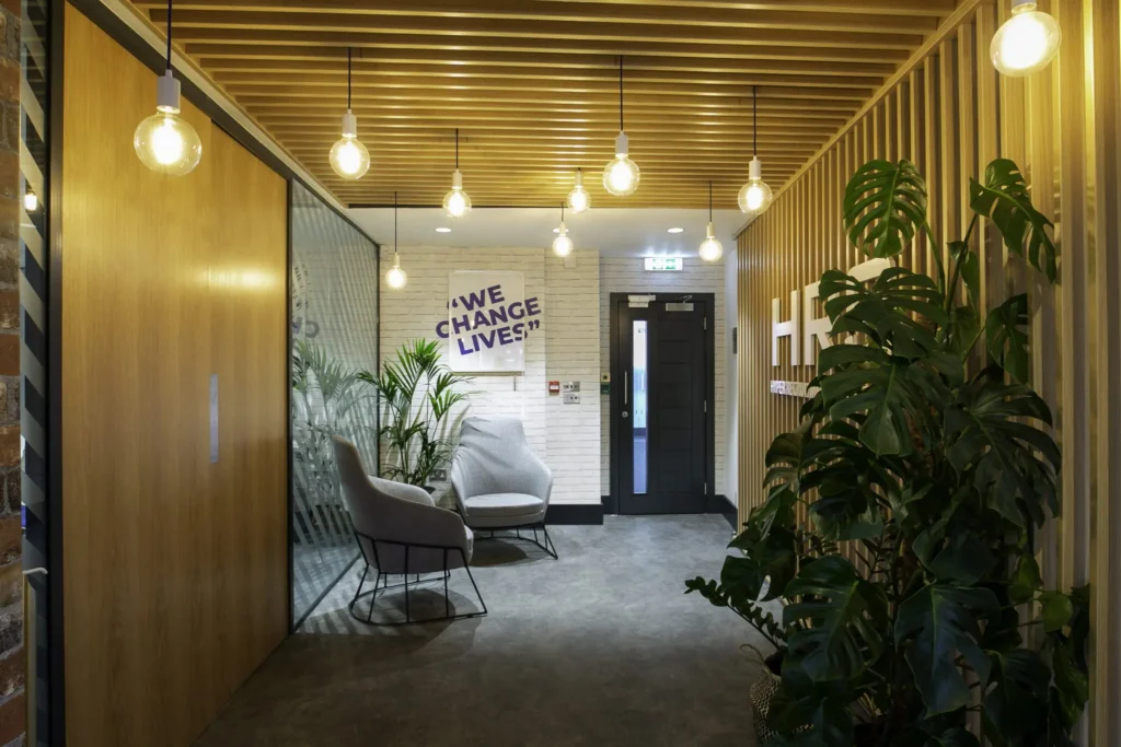 Waiting area with plants, sofa chairs and text mural